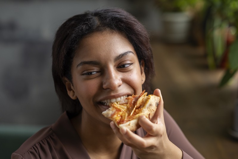 Femme vue de face, manger une délicieuse pizza